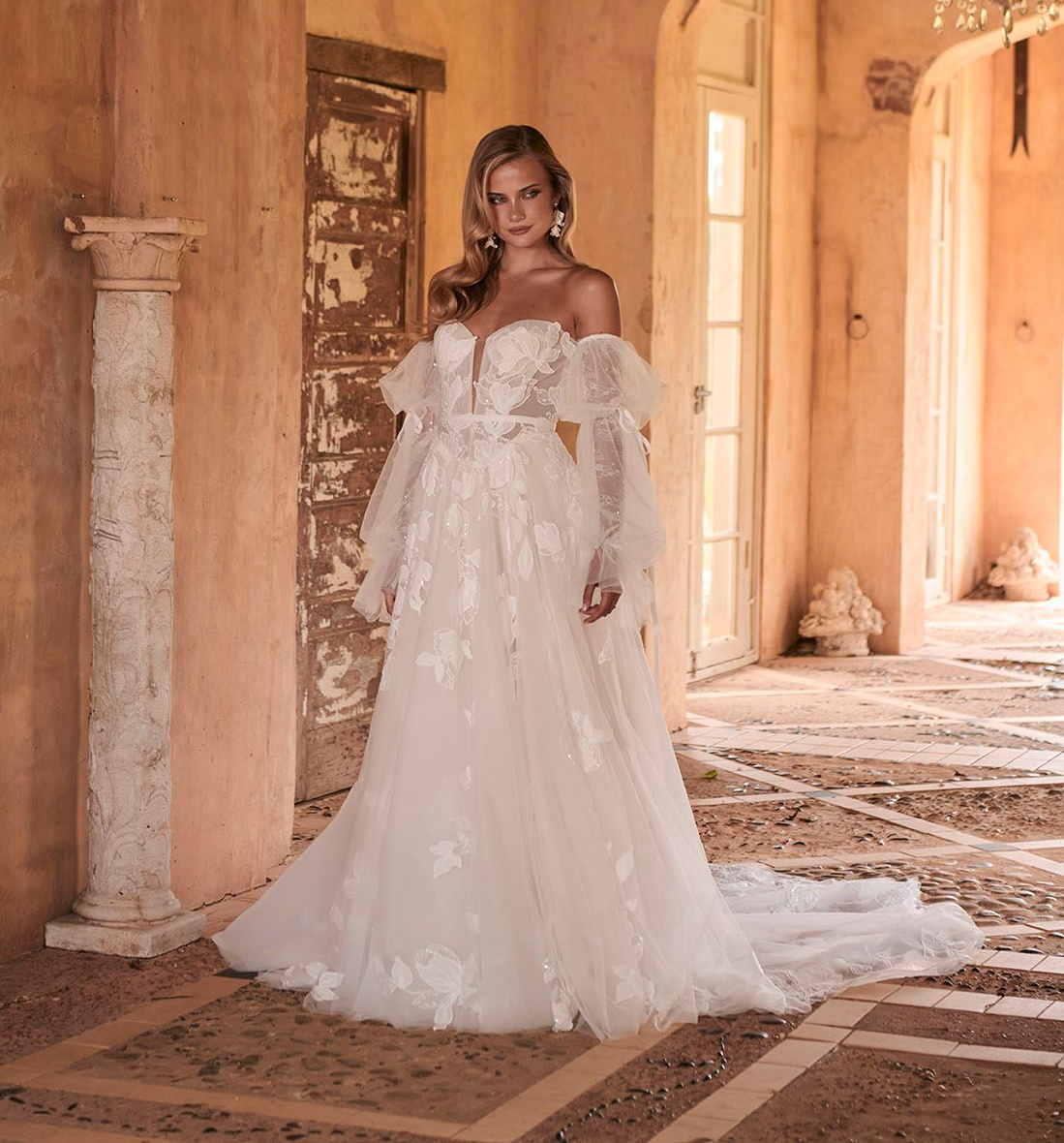 A woman in a white wedding dress is standing in a room with arches.