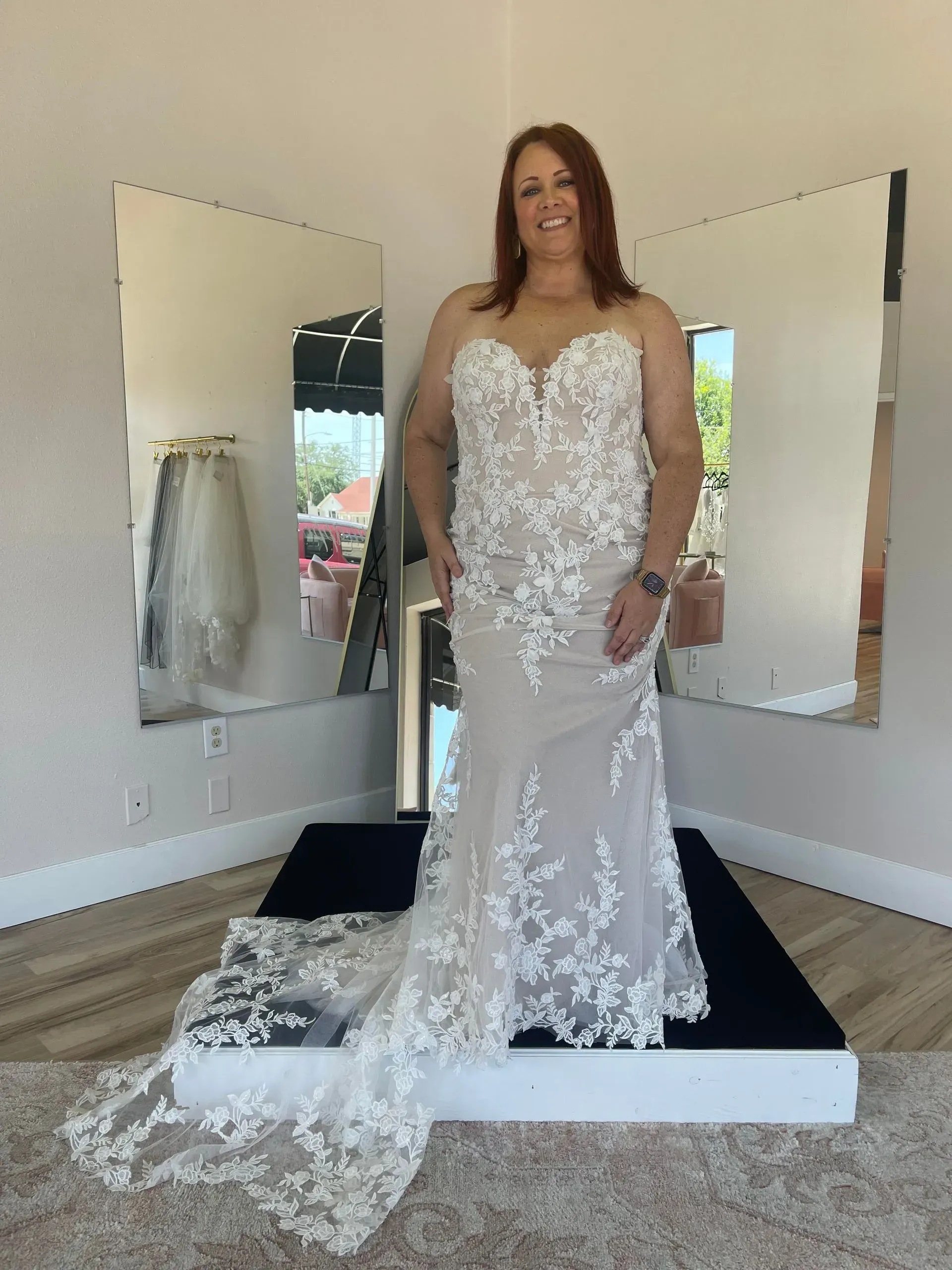 A woman is standing in front of a mirror wearing a wedding dress.