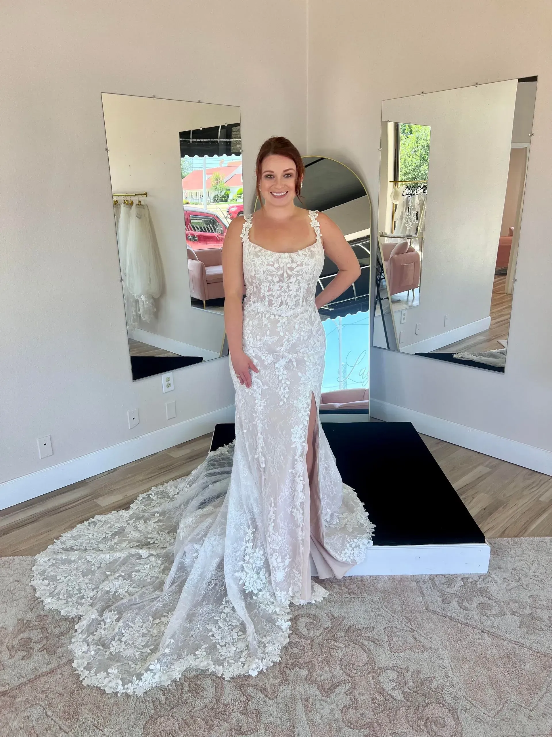 A woman in a wedding dress is standing in front of a mirror in a room.