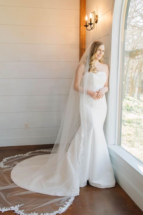 A close up of a bride in a wedding dress holding her veil.