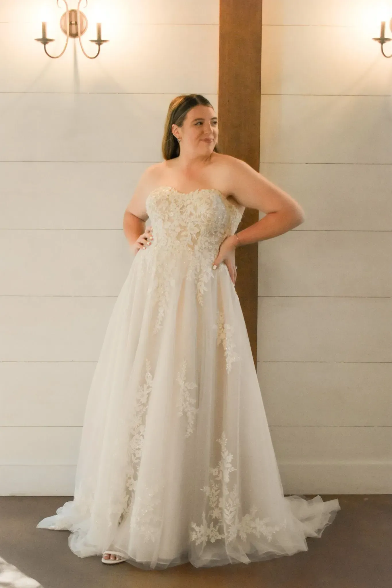 A woman is standing in a room wearing a wedding dress.