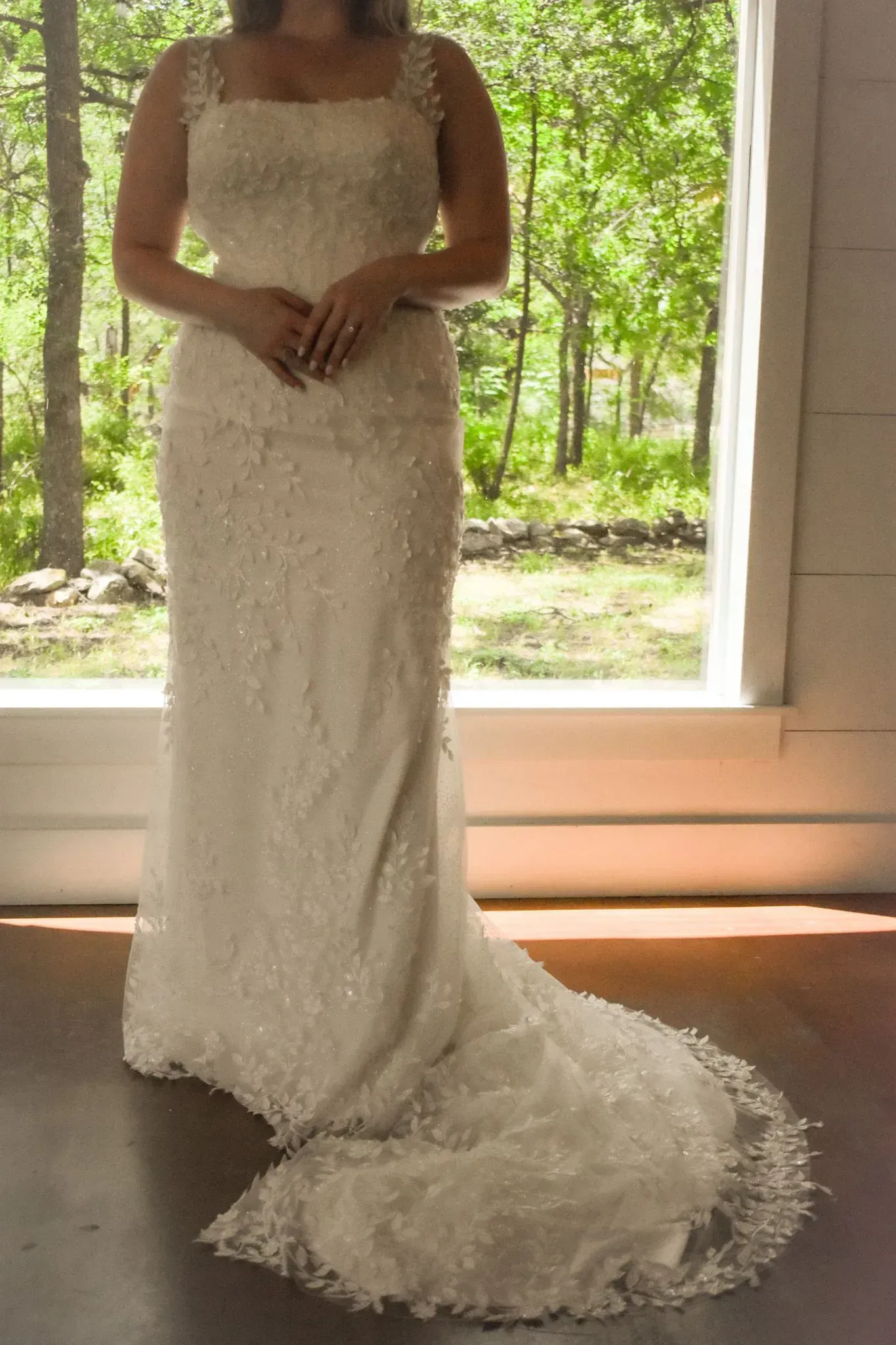 A woman in a wedding dress is standing in front of a window