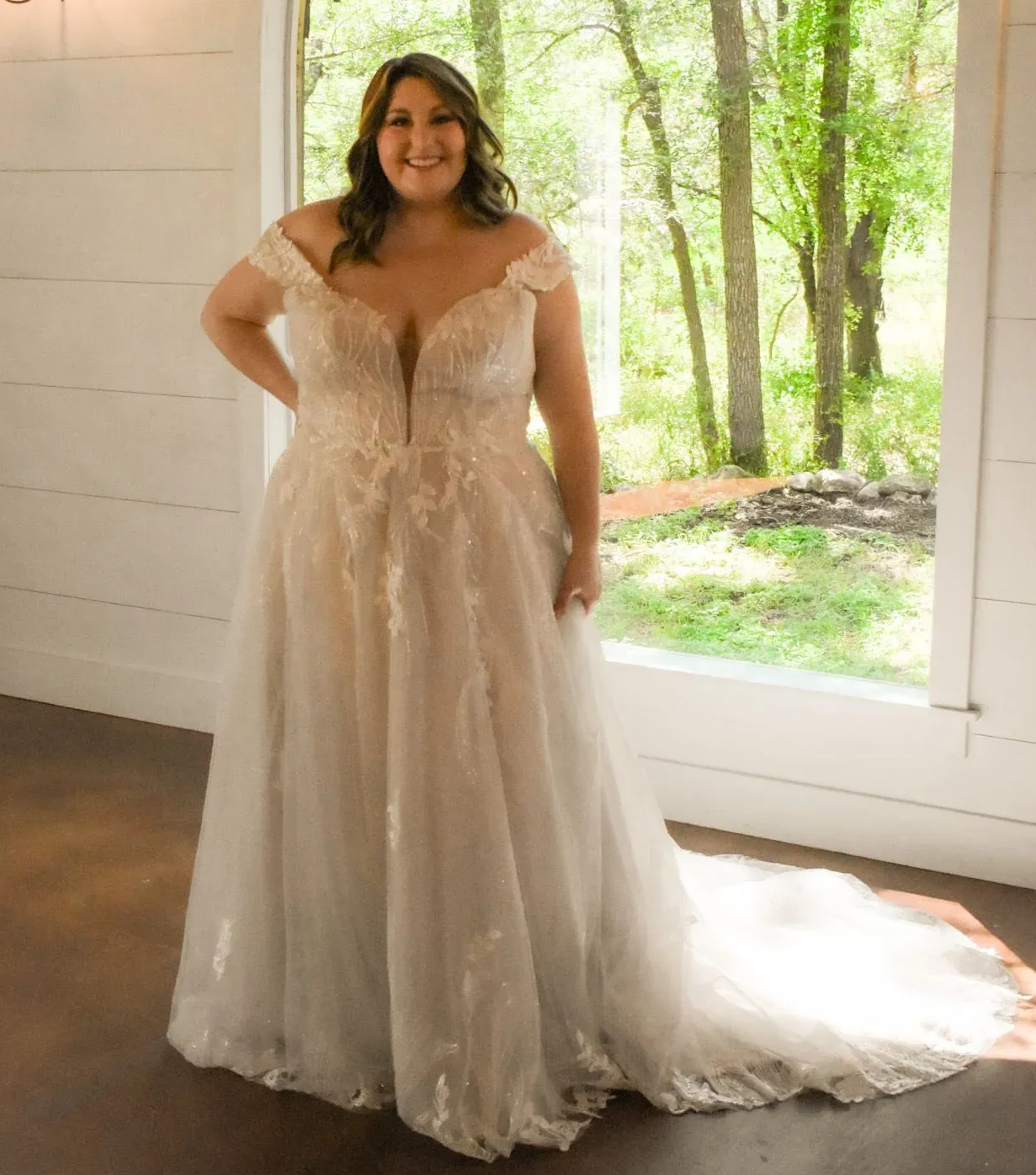 A woman in a wedding dress is standing in front of a window.