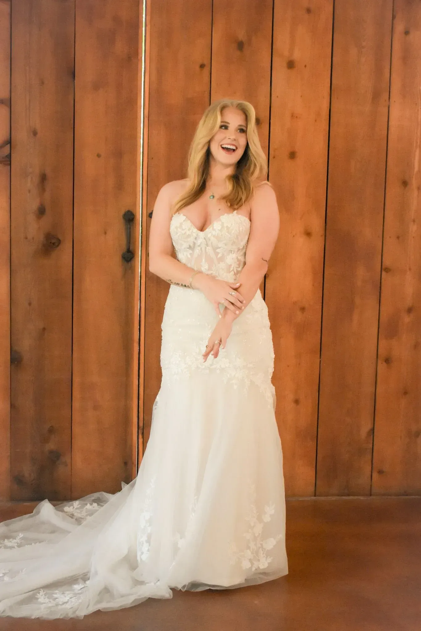 A woman in a wedding dress is standing in front of a wooden door.