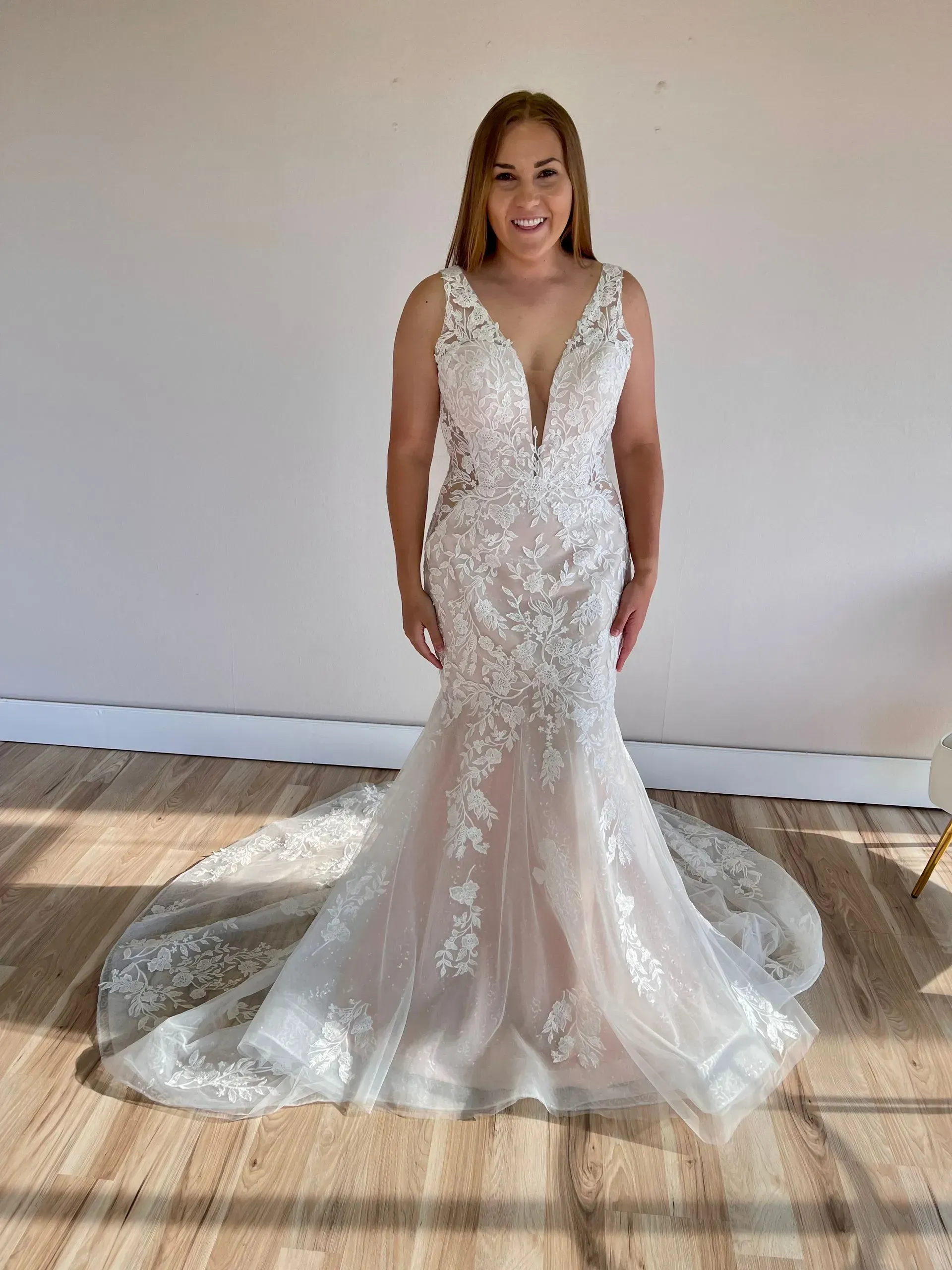 A woman is standing in a room wearing a wedding dress.