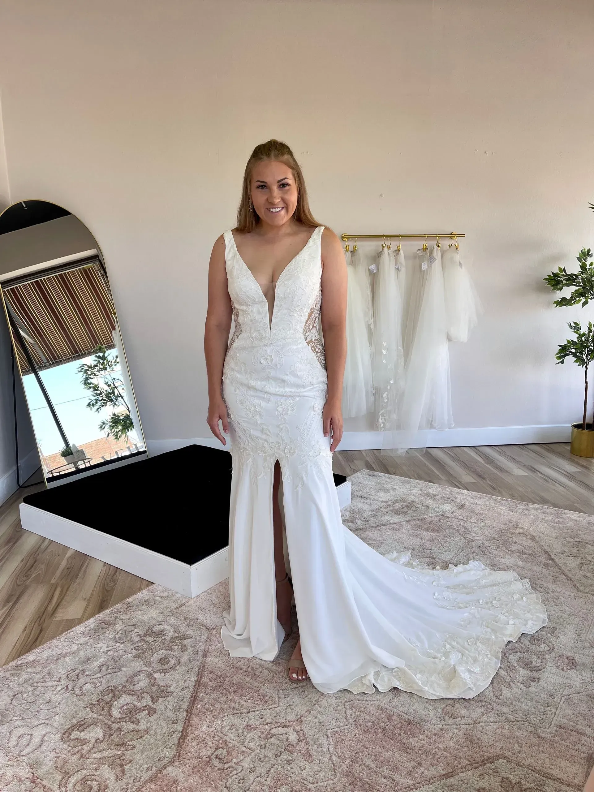 A woman in a white wedding dress is standing in front of a mirror.