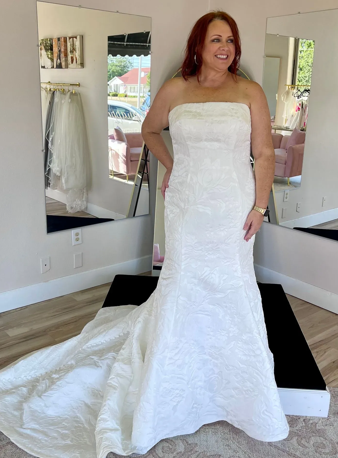 A woman in a white wedding dress is standing in front of a mirror.