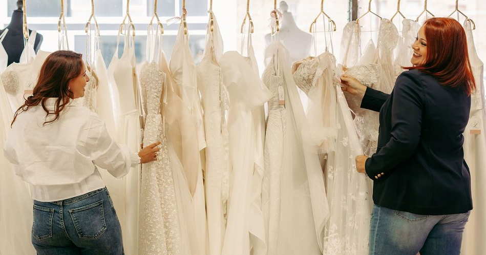 A bride in a wedding dress is sitting on the ground holding a bouquet of flowers.