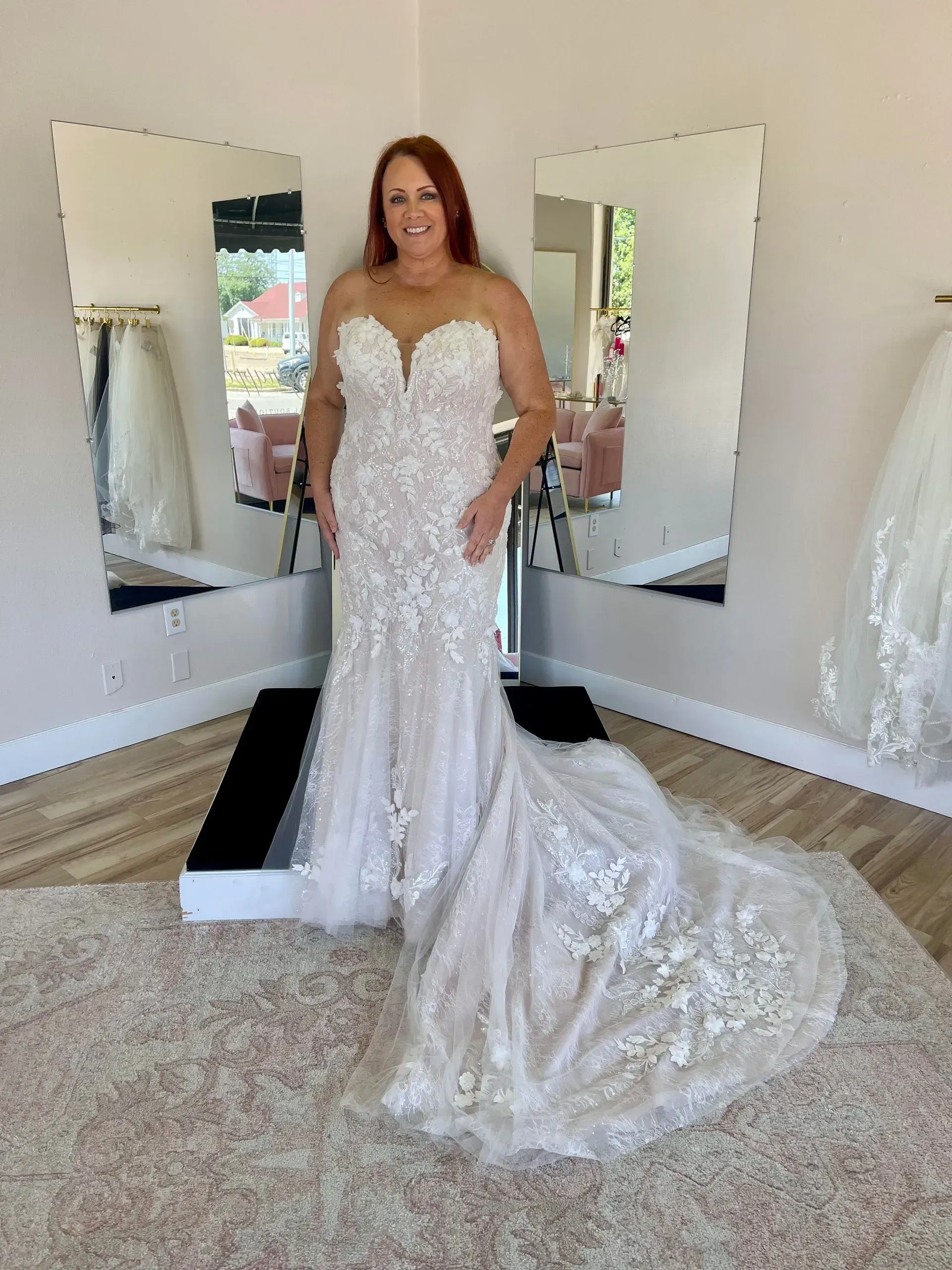 A woman in a wedding dress is standing in front of a mirror in a room.