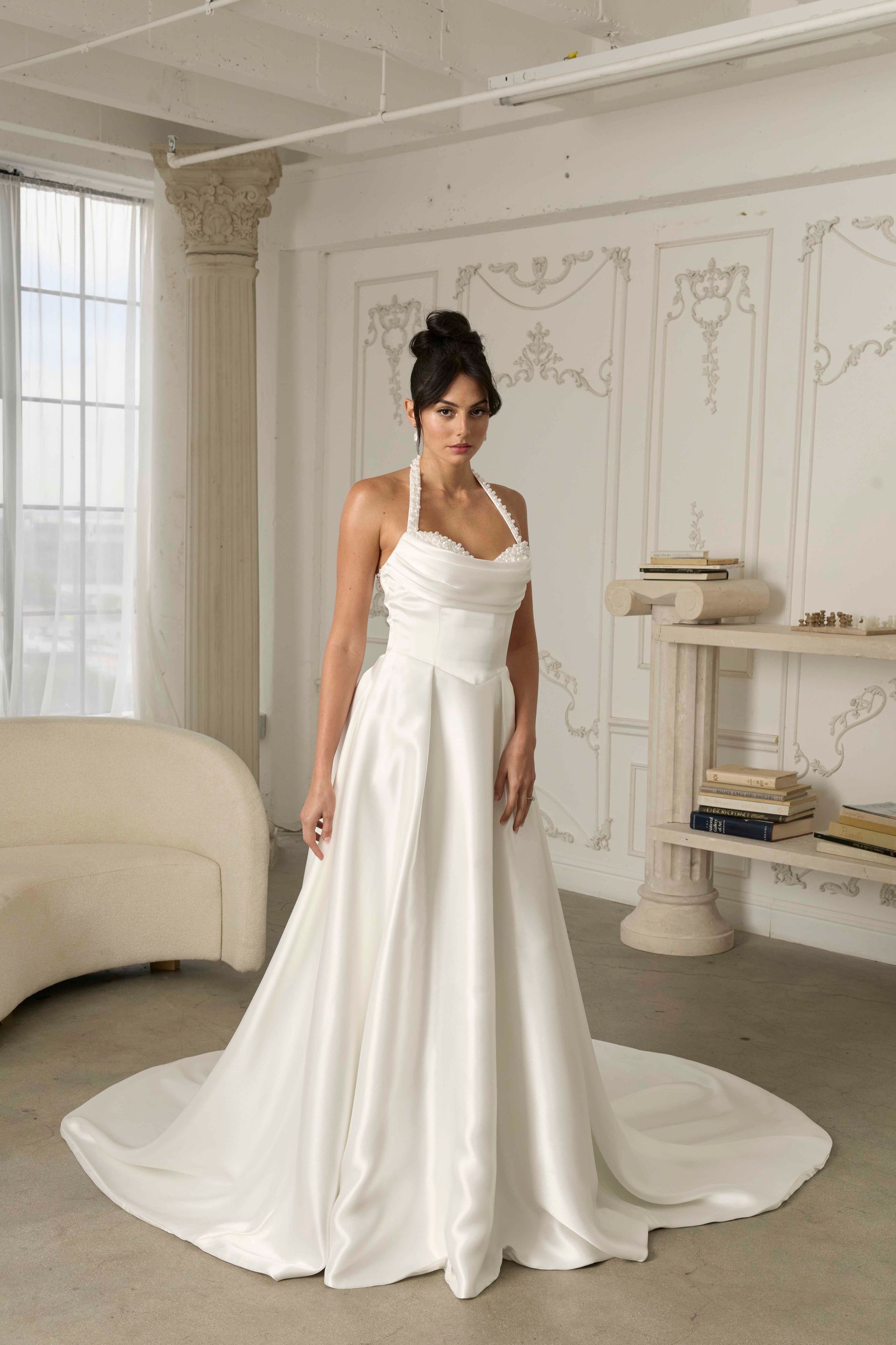 A woman in a white wedding dress is standing in front of a fireplace.