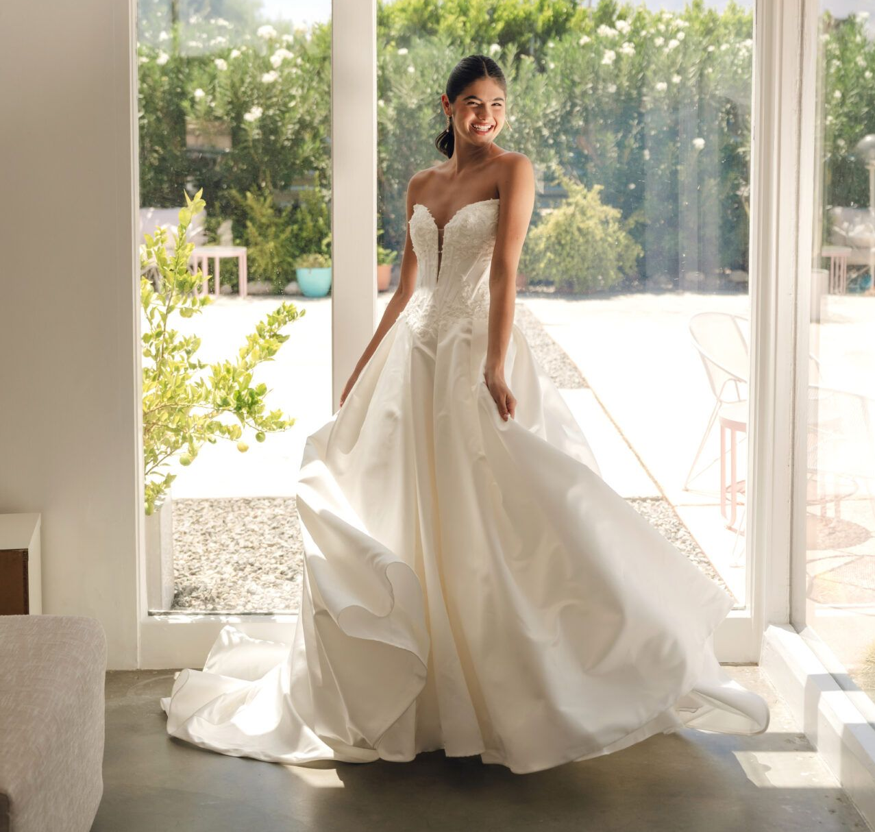 A woman in a white wedding dress is standing in front of a brick building.
