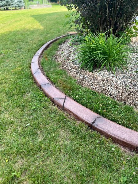 A concrete curb is sitting in the middle of a lush green lawn.