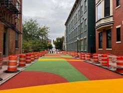 A colorful street is being painted in front of a building.