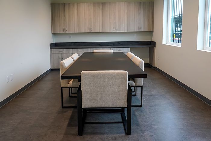 Modern conference room with a long table, beige chairs, and wood cabinets along the back wall