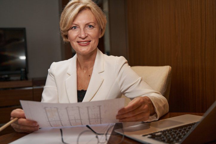 A smiling businesswoman sitting at her desk holding a piece of paper