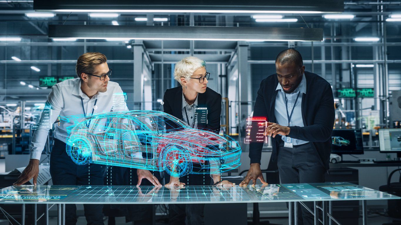 Three business people work on a virtual model of a car