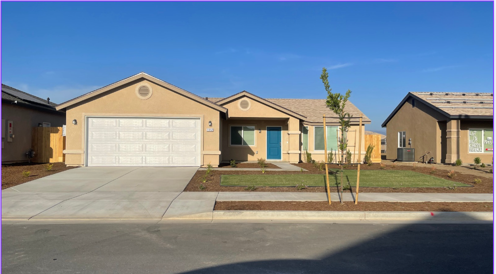 Tan house with white garage door, teal front door, and blue sky.