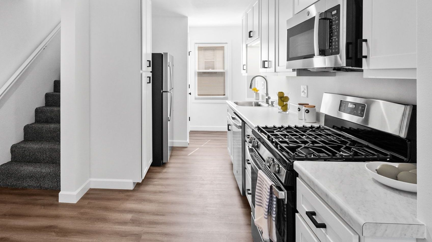 Wide shot of modern kitchen with white cabinets and stainless appliances