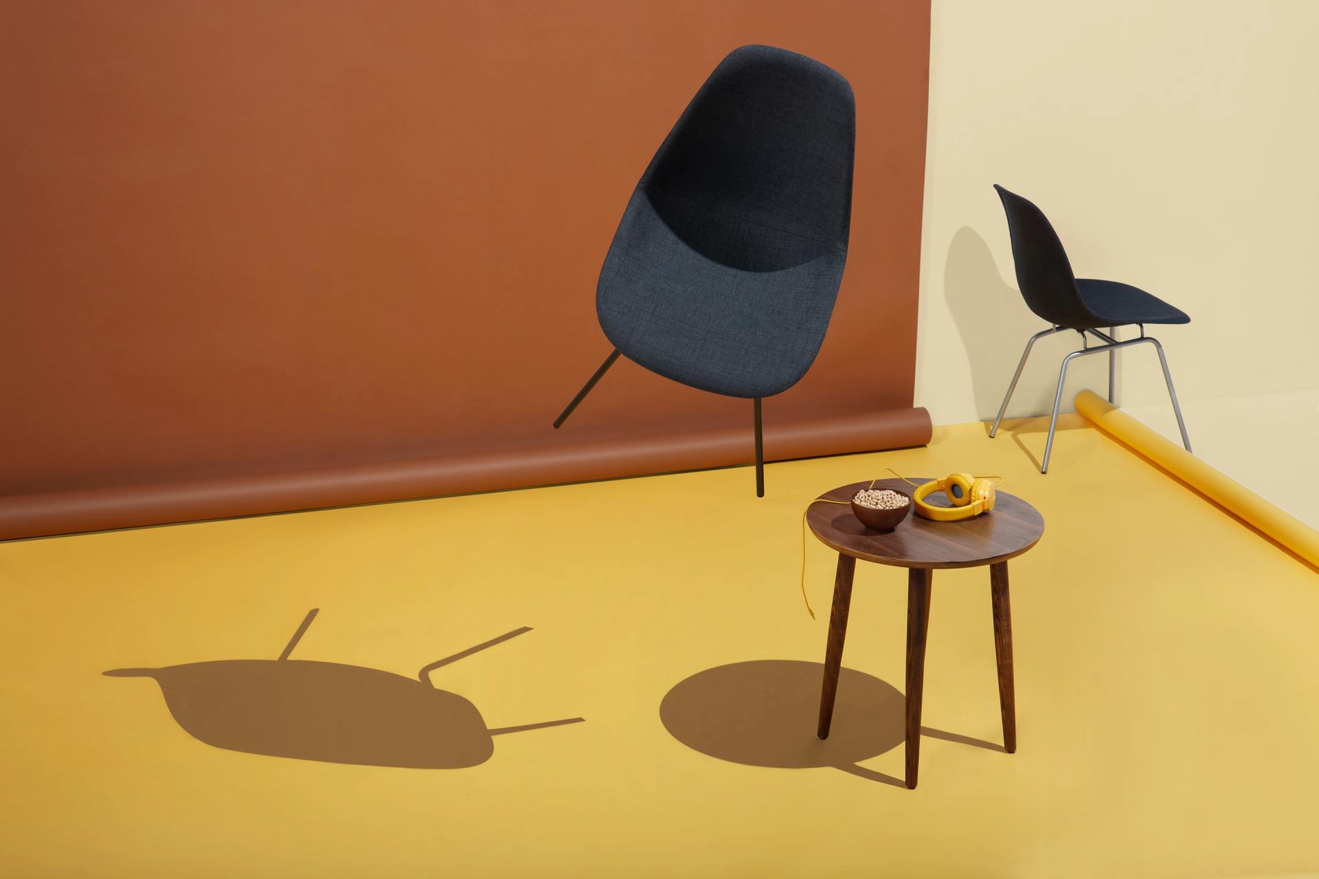 Two chairs, one floating, and a small table with snacks against a brown and yellow backdrop.