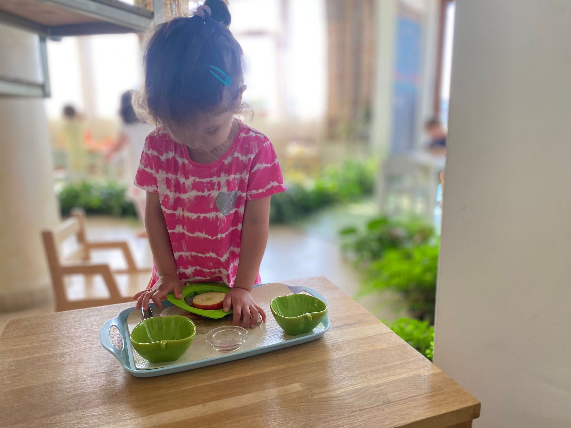 A little girl is playing with a tray of food on a table.