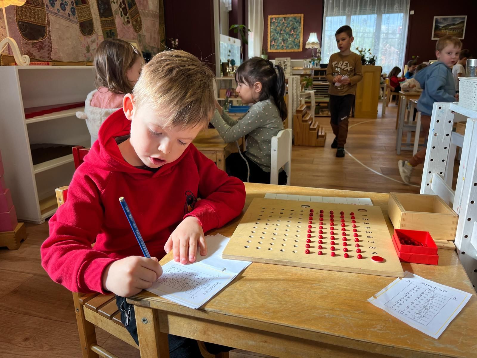 Un baiat de scoala primara lucrand inmultiri cu materiale Montessori la scoala primara a Liceului Montessori Cluj