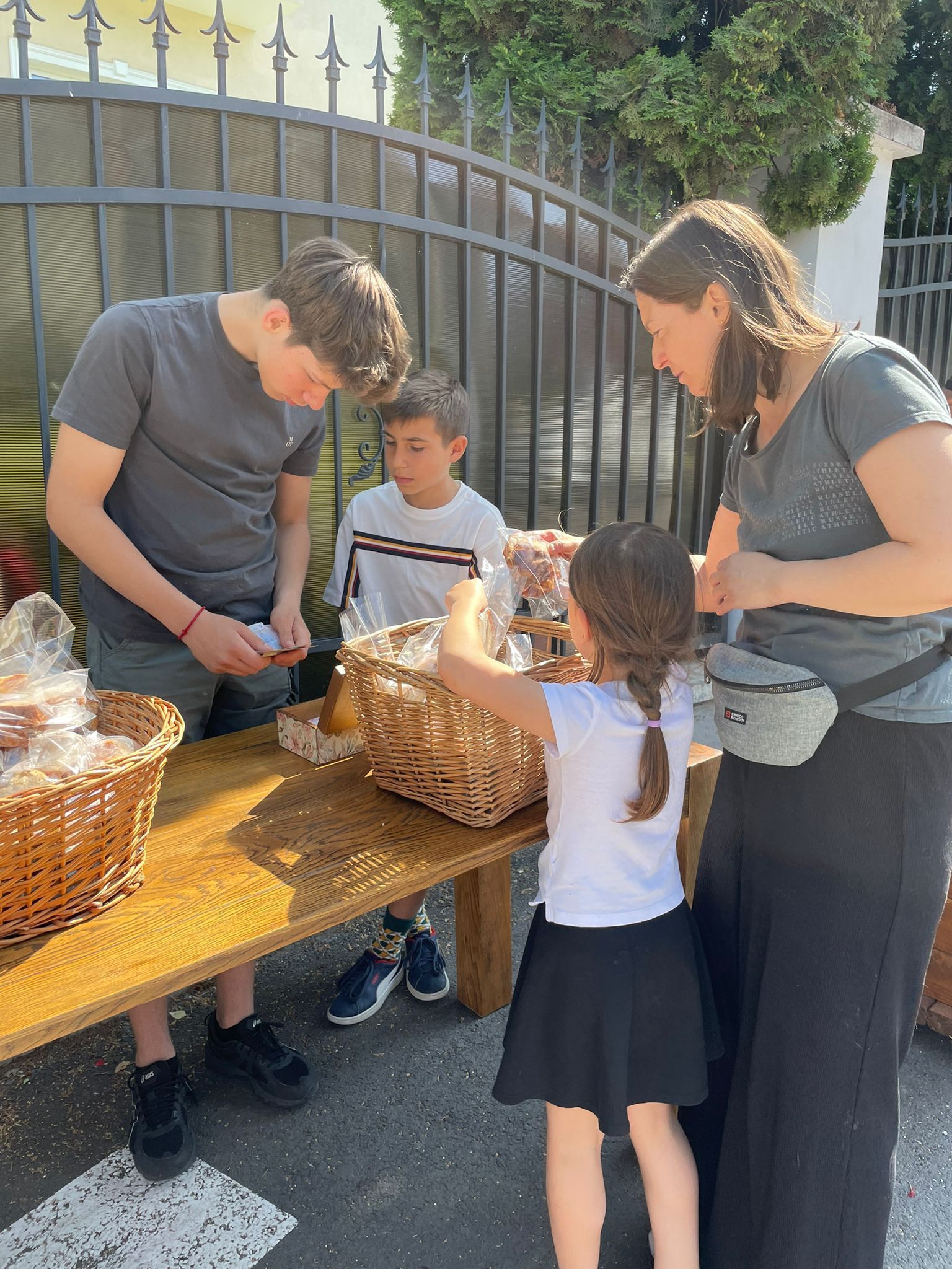 A family is standing around a table with baskets of food.