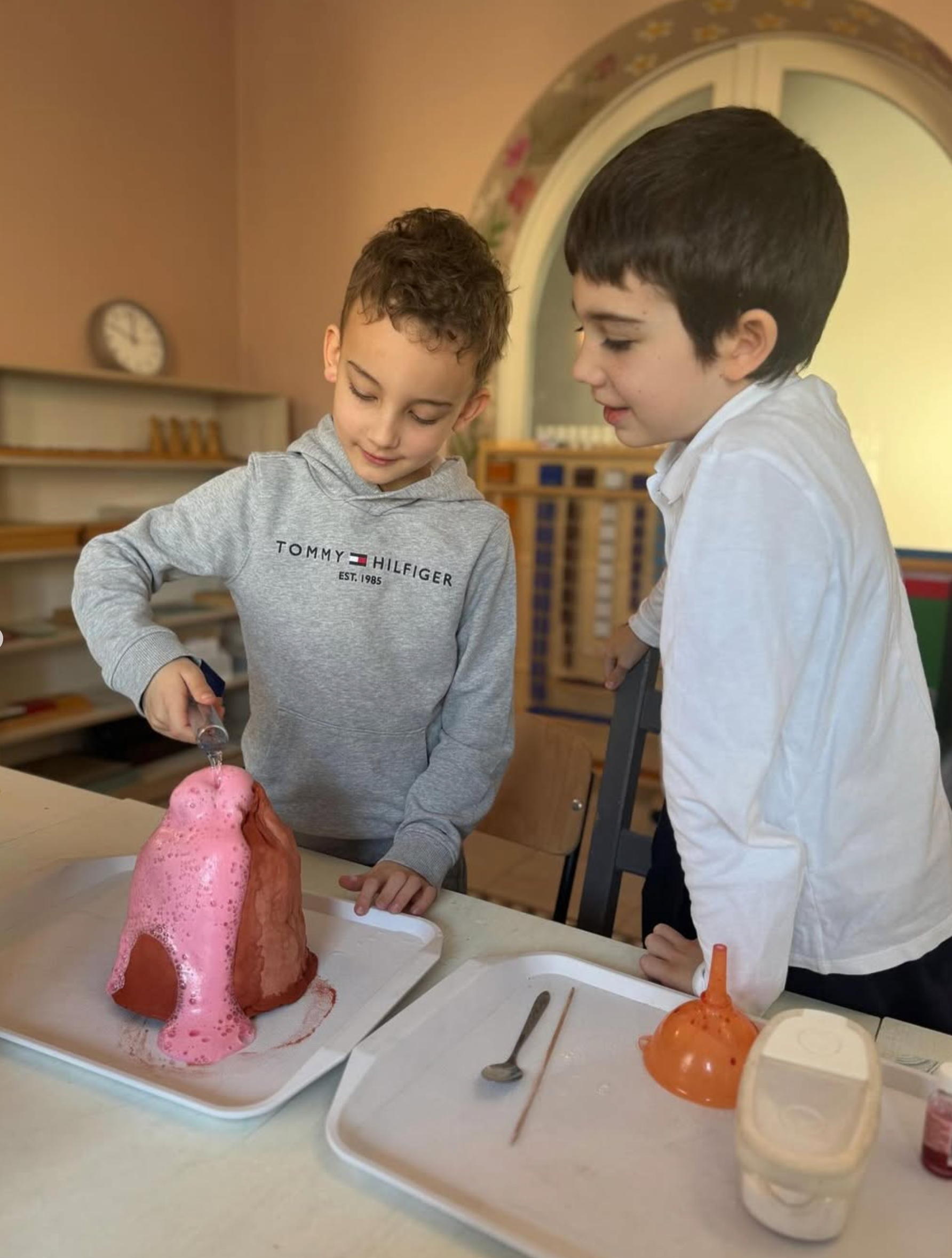Two young boys are playing with a cake on a table