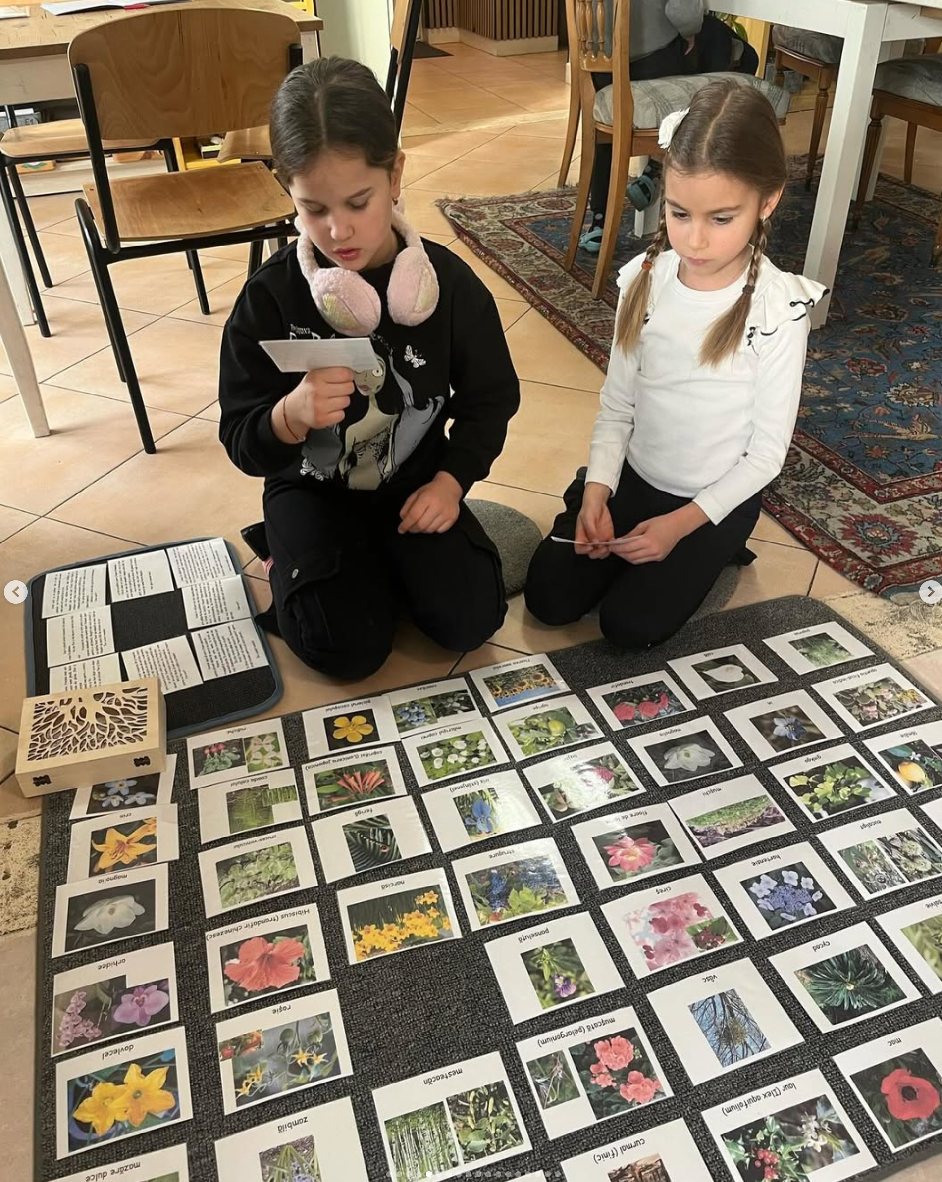 Two young girls are sitting on the floor playing a game.