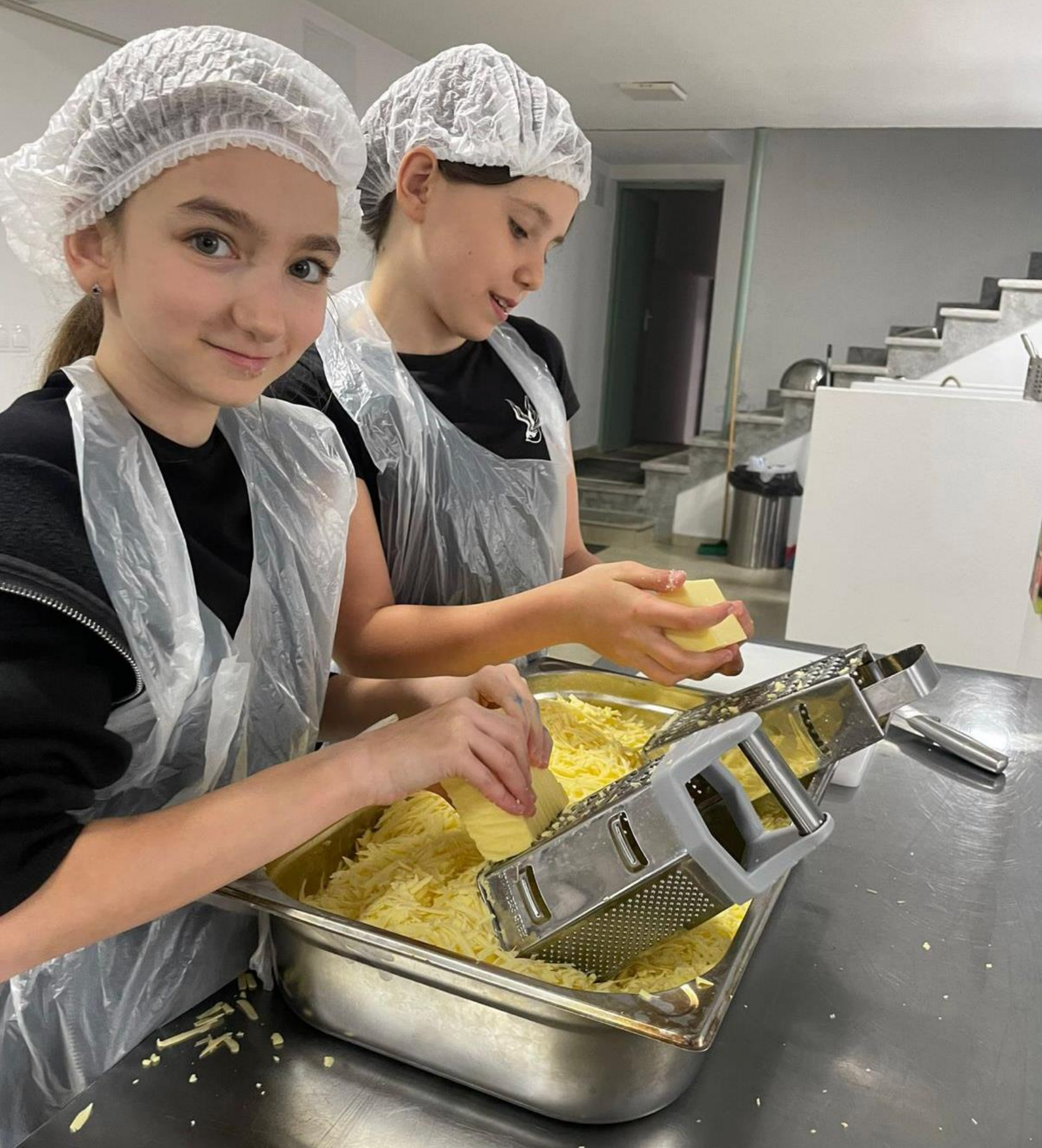 Two young girls are preparing food in a kitchen