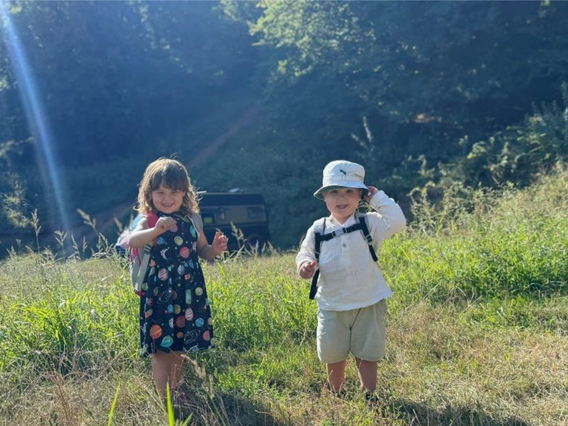 A boy and a girl are standing in a grassy field.