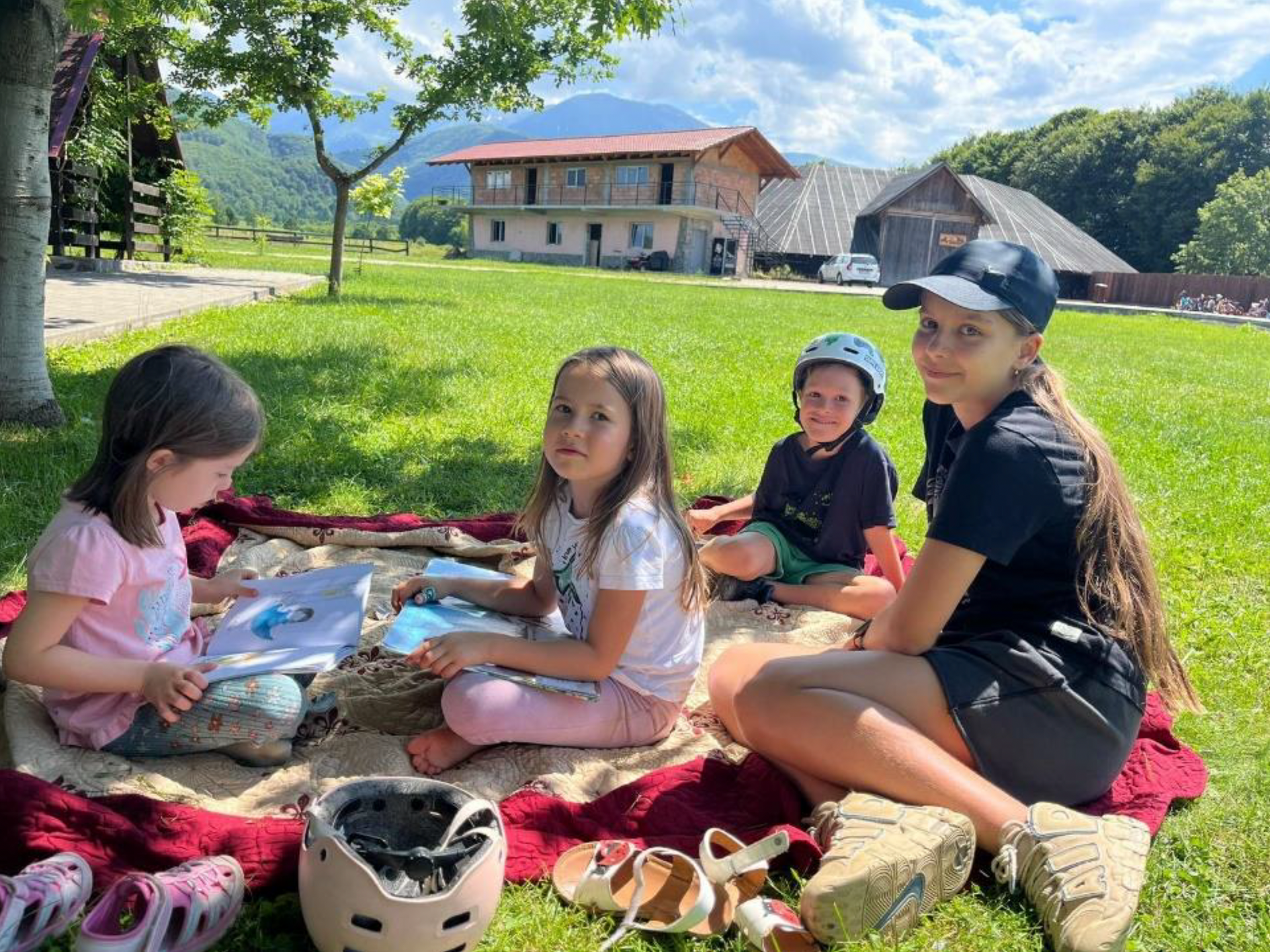 A group of children are sitting on a blanket in the grass.