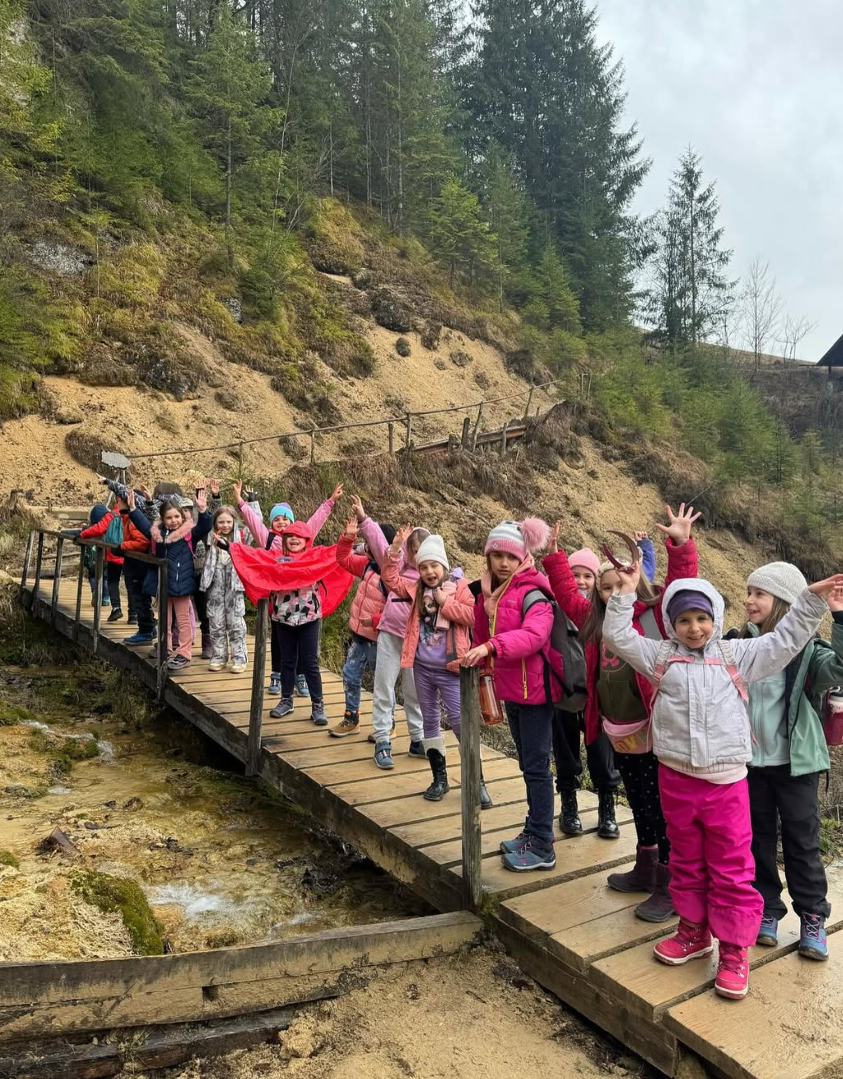A group of children are standing on a wooden bridge.
