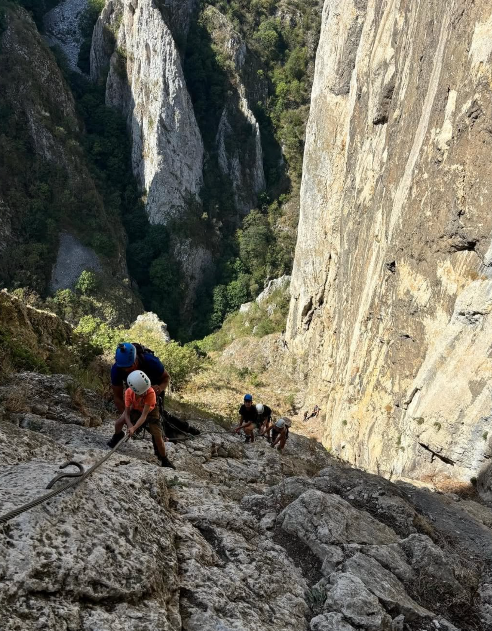 A group of people are climbing up a rocky cliff.