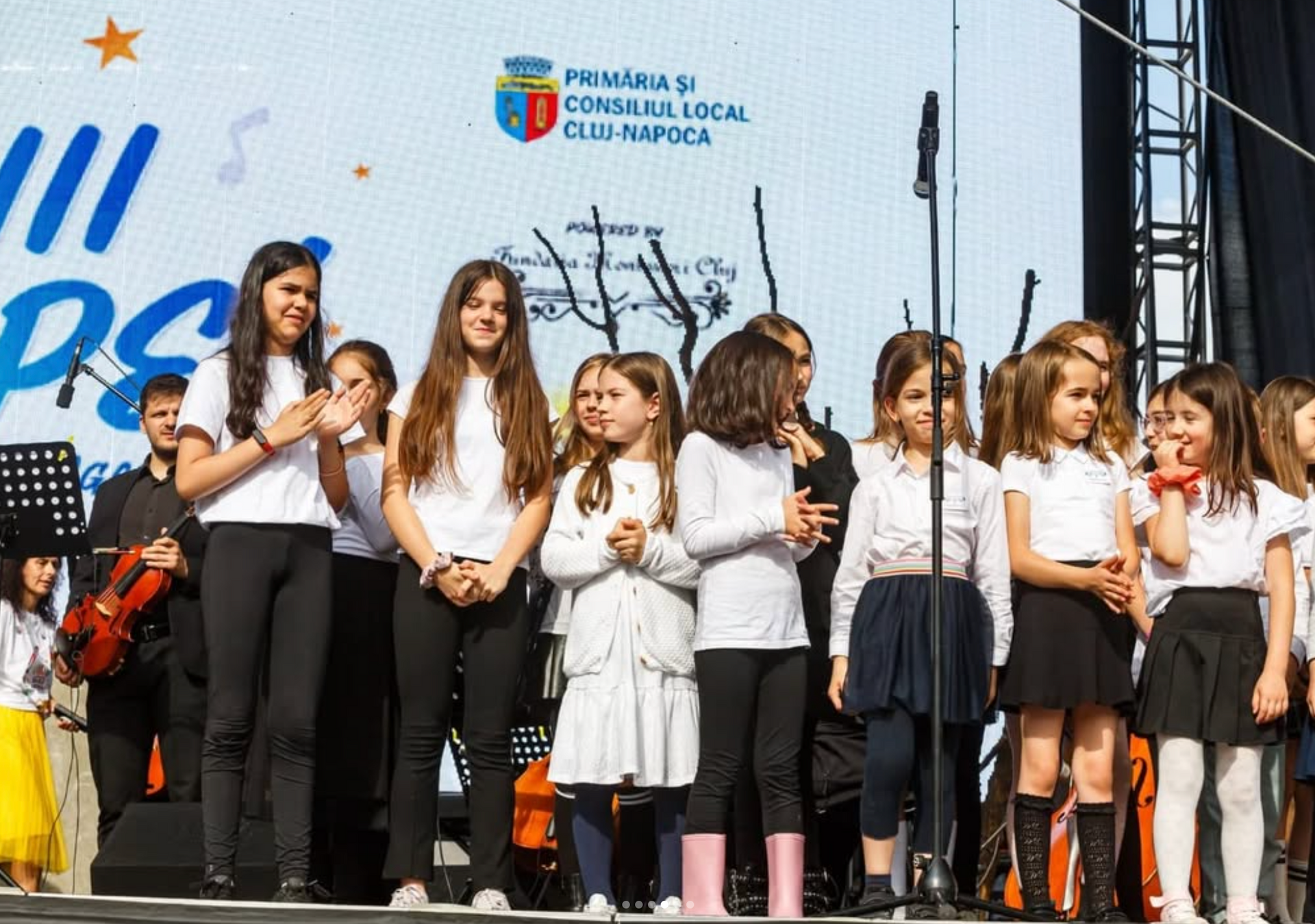 A group of young girls are standing on a stage singing into microphones.