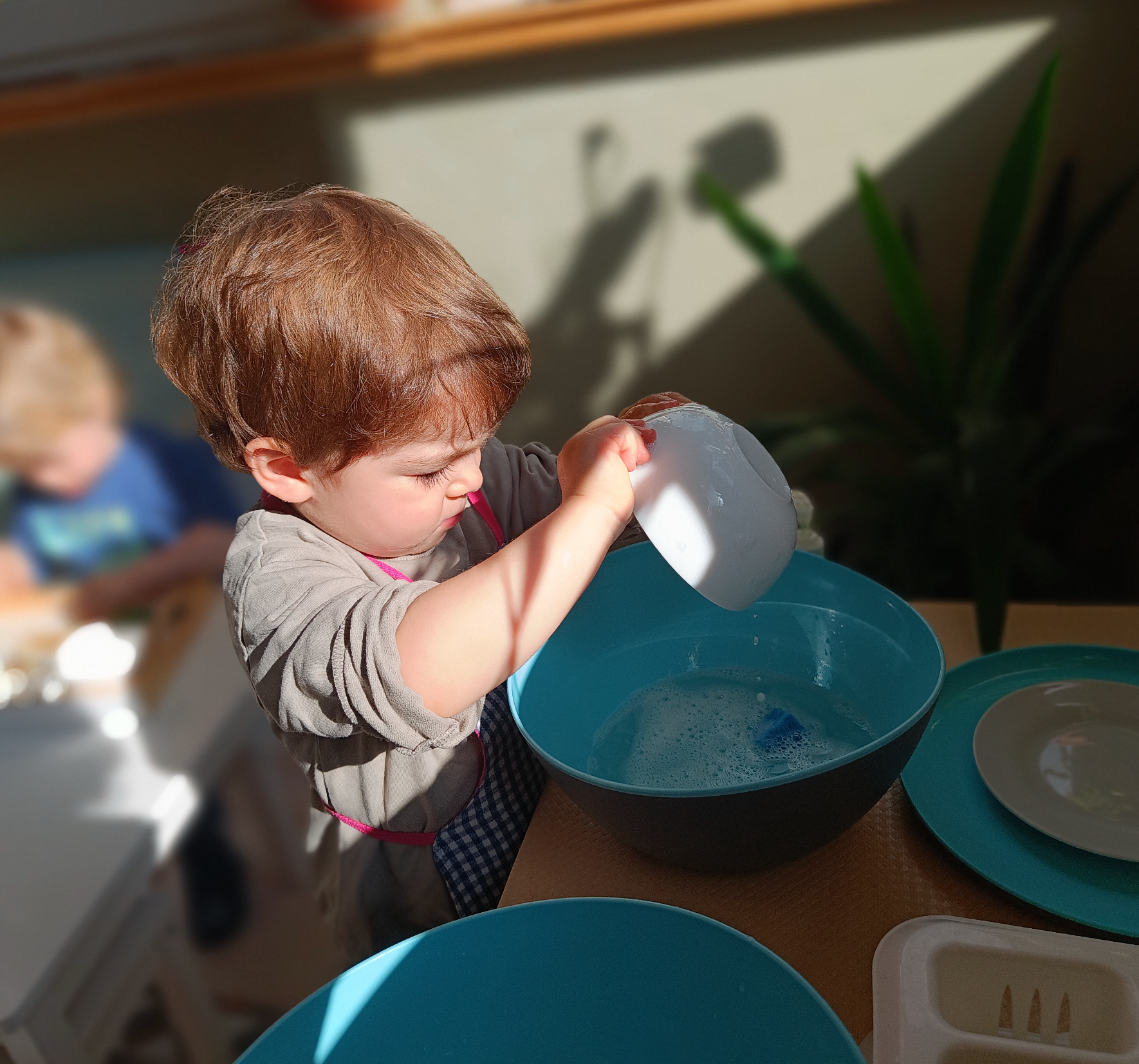 A little boy is playing with a bowl of water