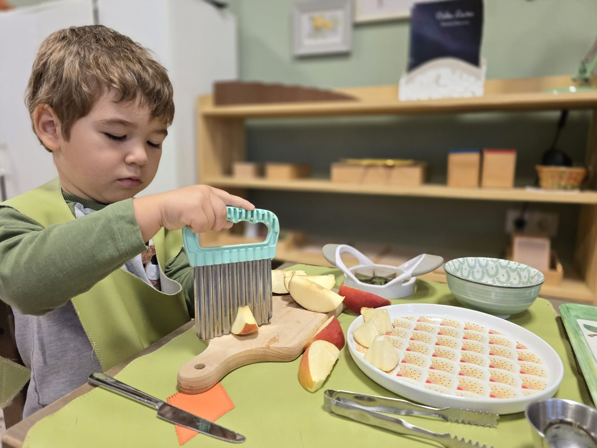 A young boy is cutting apples on a cutting board.