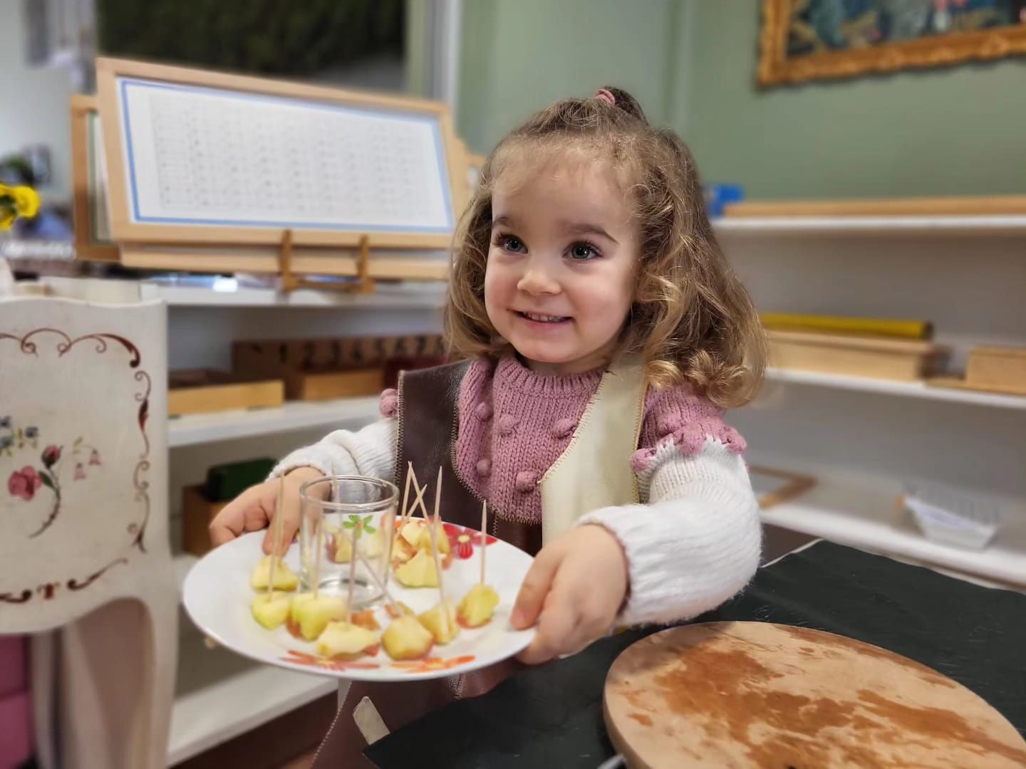 A little girl is holding a plate of apples, a healthy snack.