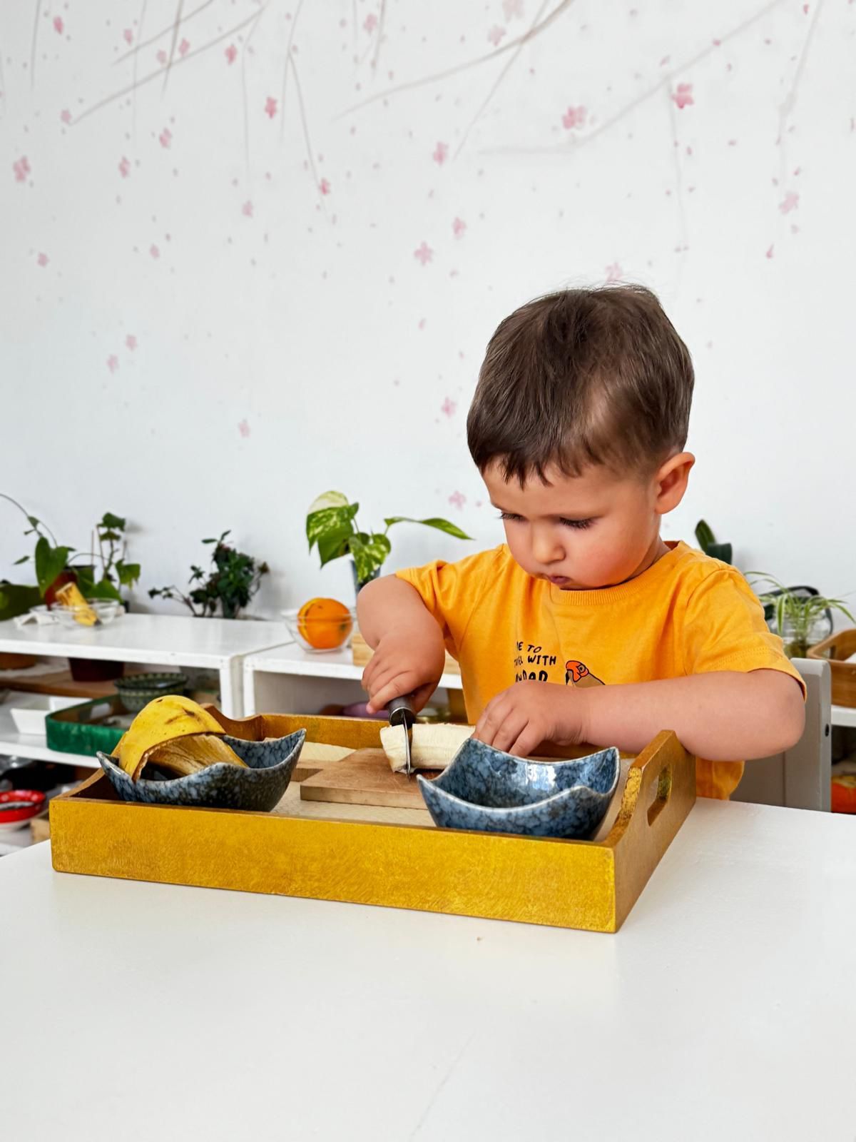 A young boy is playing with a wooden tray on a table.