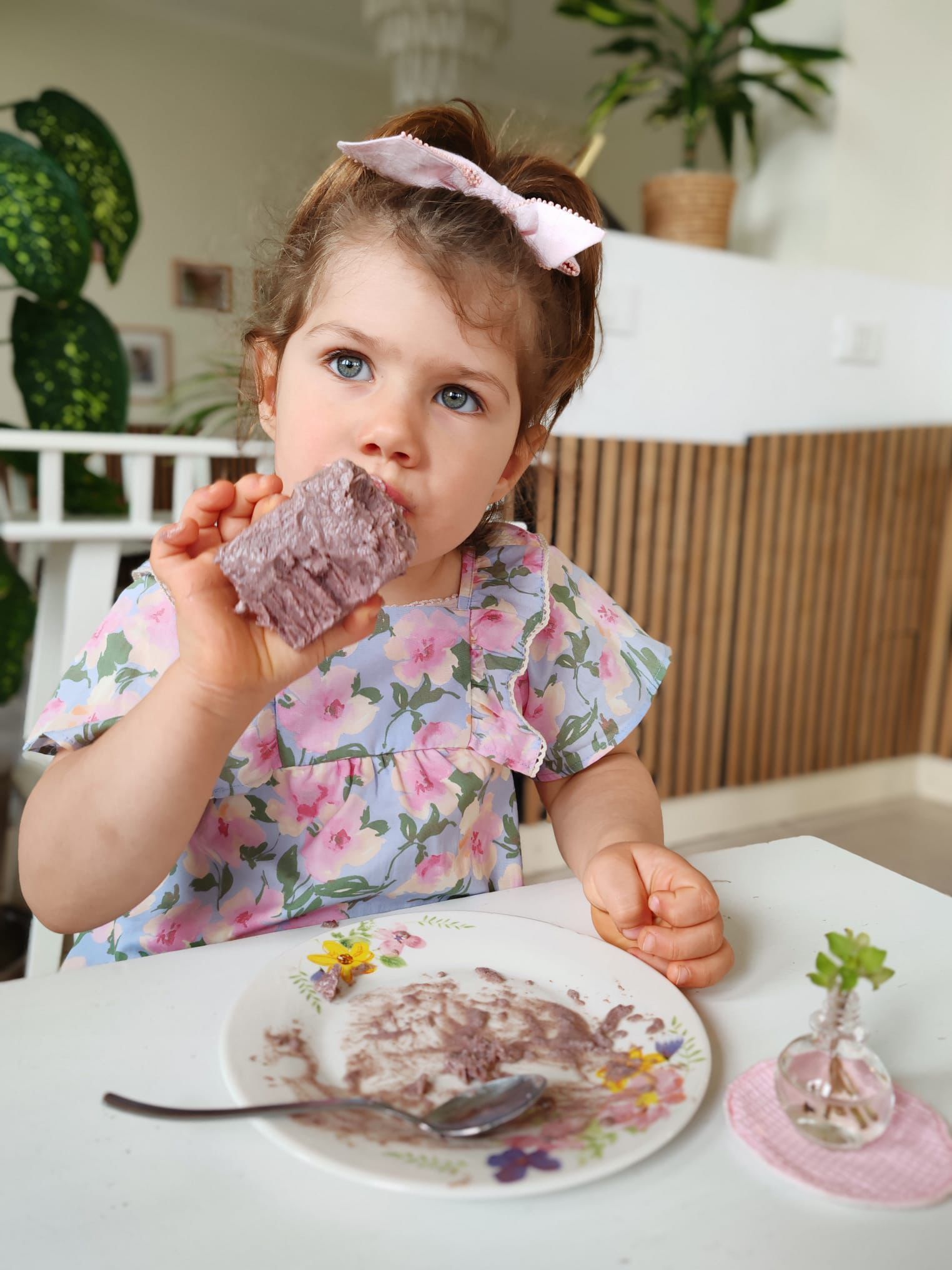 A little girl is sitting at a table eating a piece of cake.