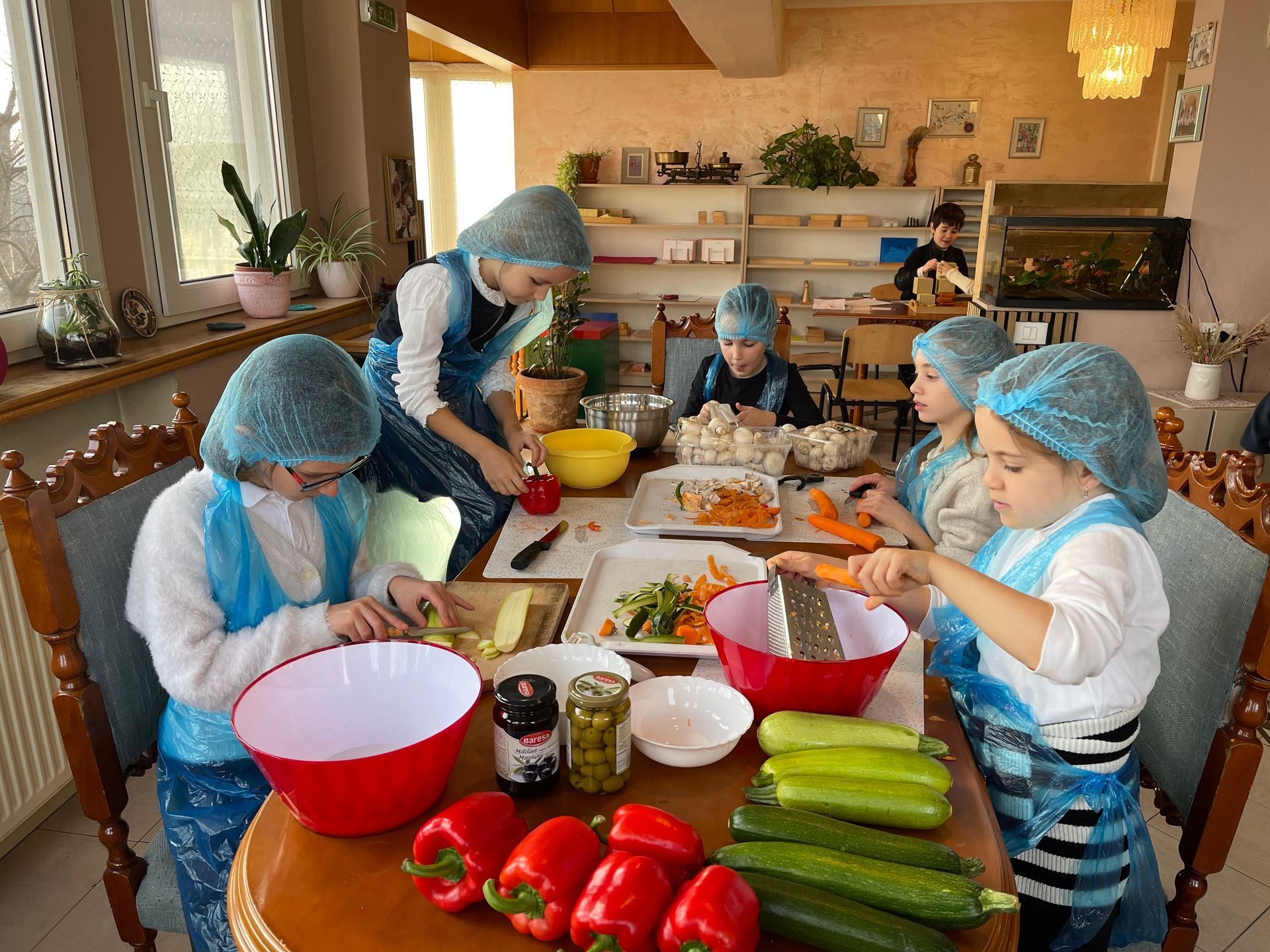 A group of children are sitting around a table cutting vegetables
