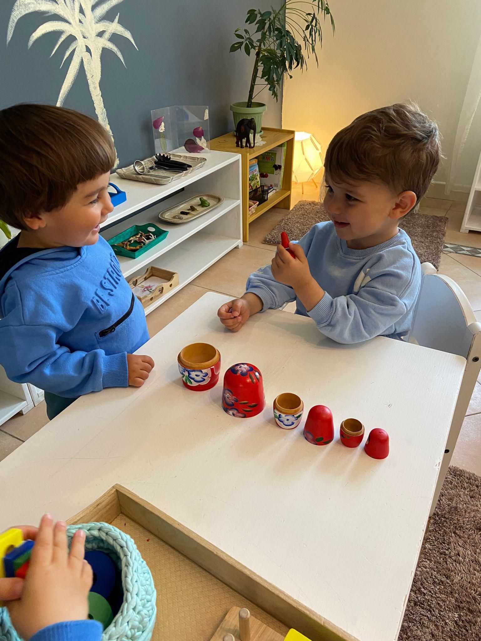 Two young boys are sitting at a table playing with toys.