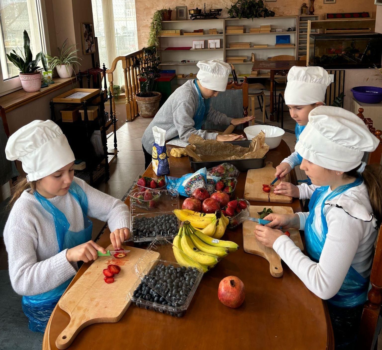 Un grup de copii de scoala primara gatind salata de fructe la scoala Montessori Cluj