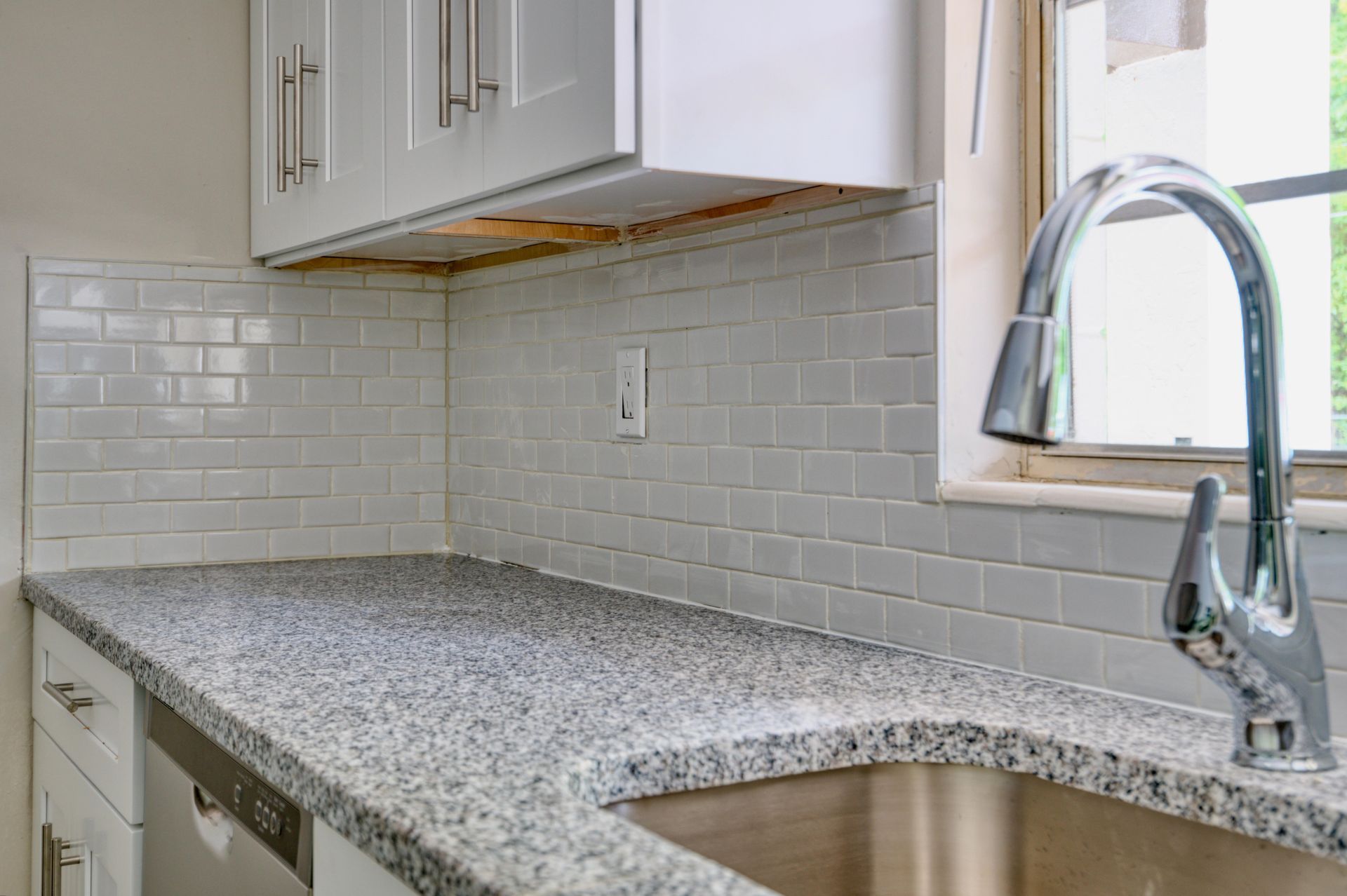 A kitchen with granite counter tops and a stainless steel sink.