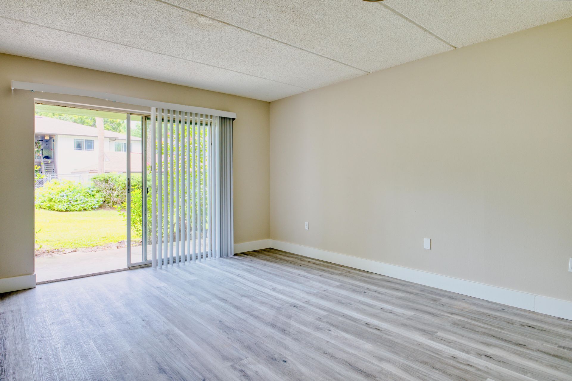 An empty living room with sliding glass doors and hardwood floors.