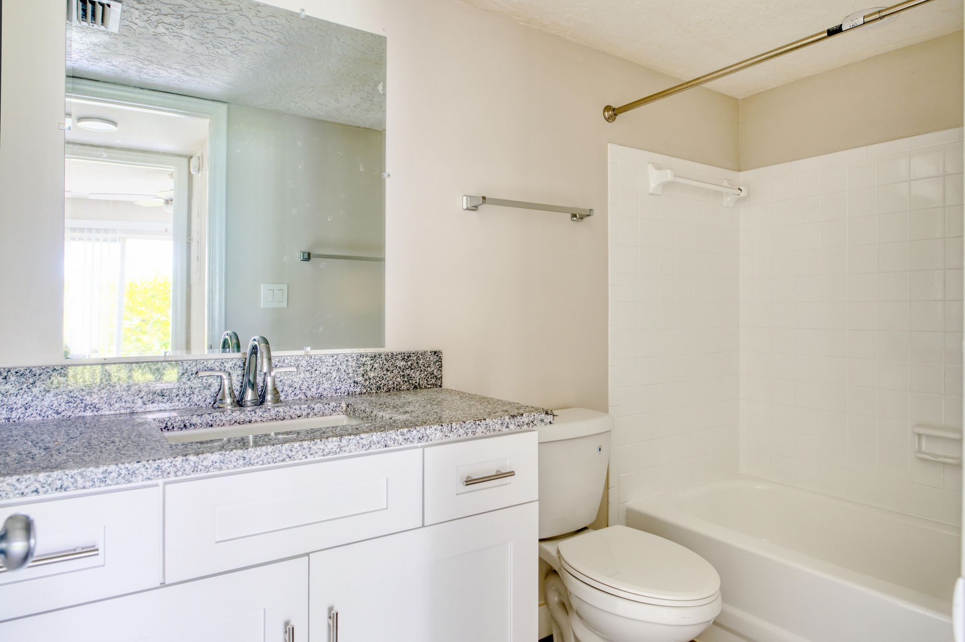 A bathroom with a sink , toilet , tub and mirror.