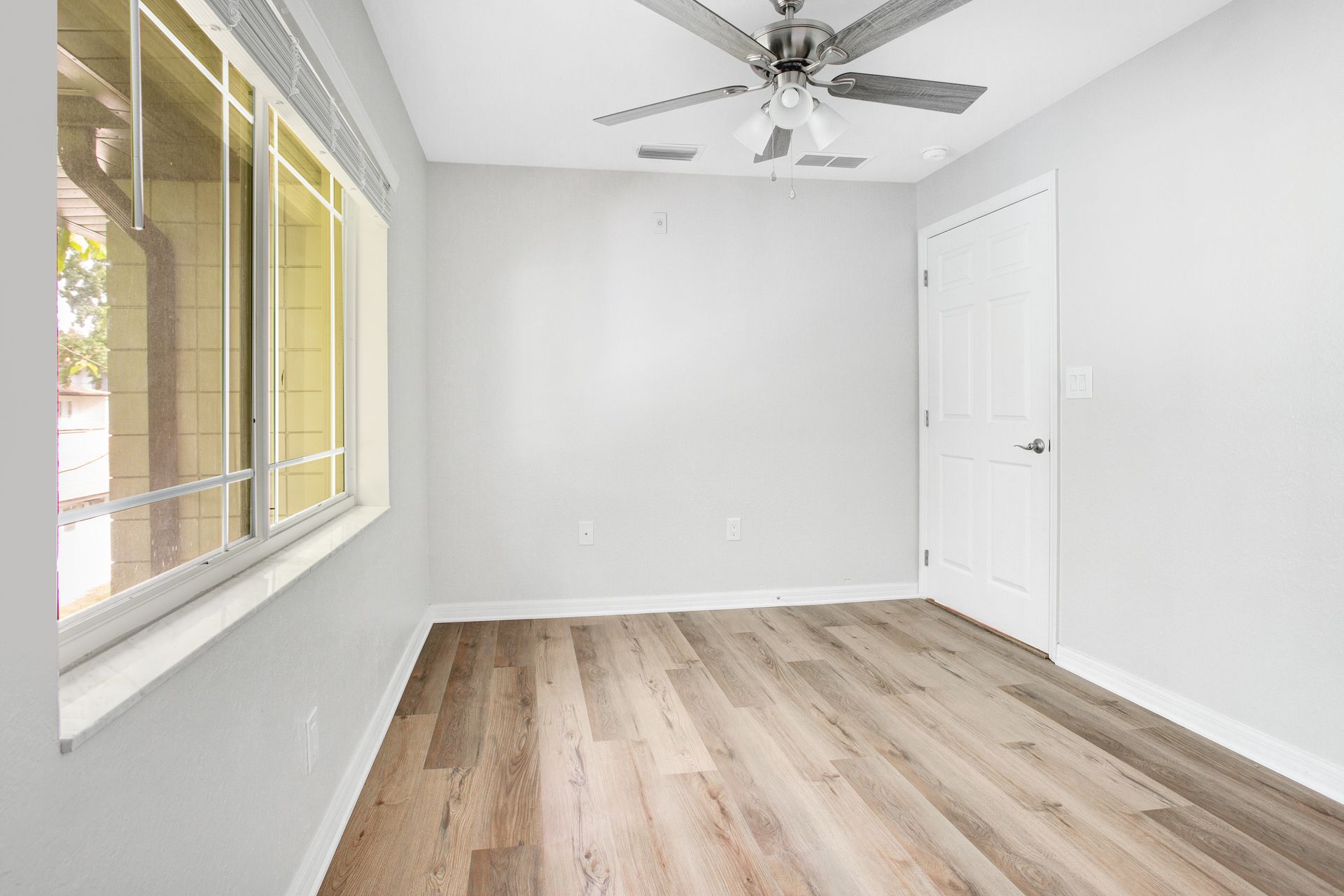A modern bedroom with vinyl wood floors and a ceiling fan.