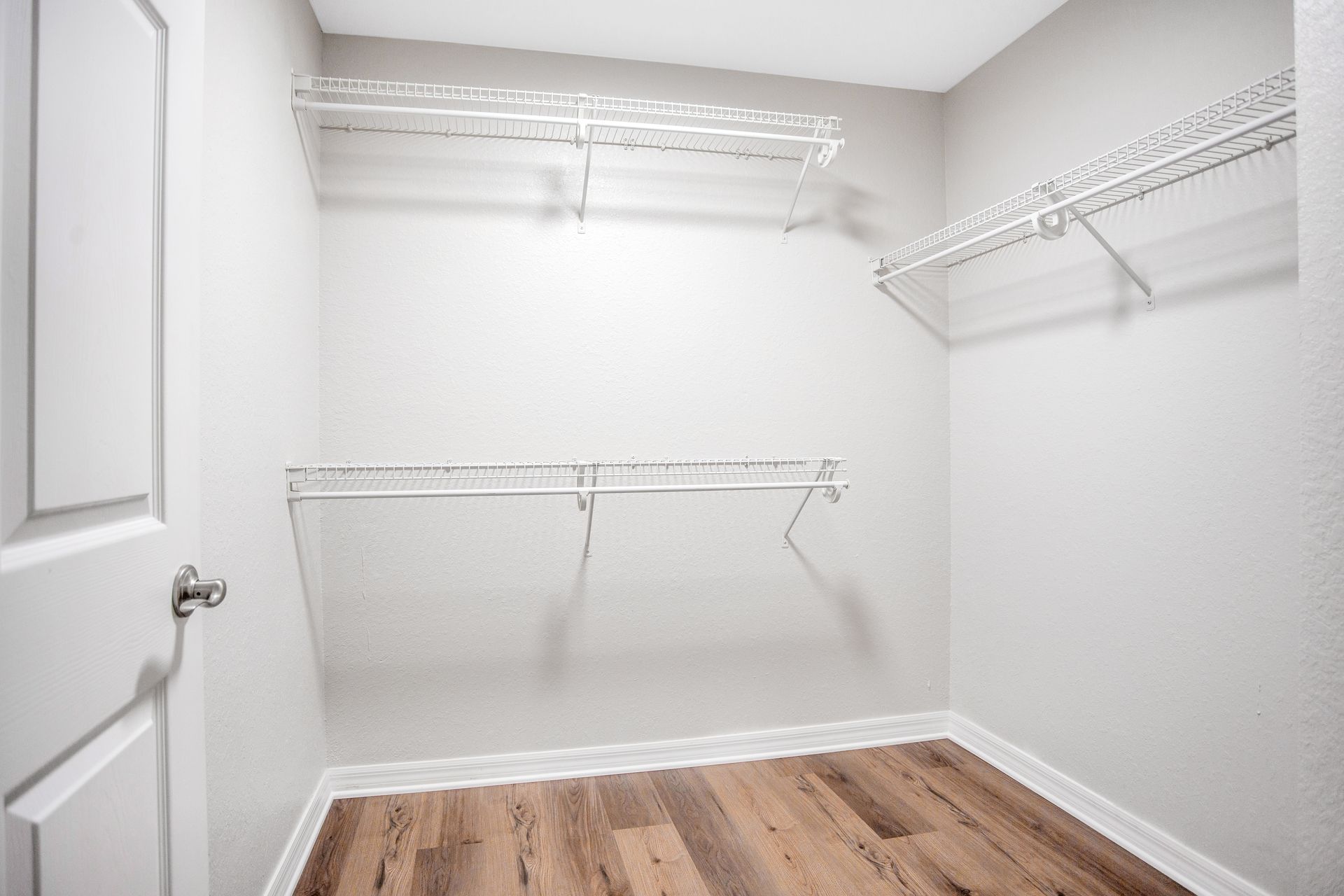 An empty walk in closet with vinyl floors and shelves.