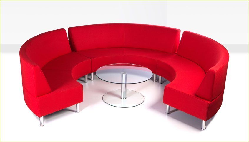 a red round couch with a round glass table in front