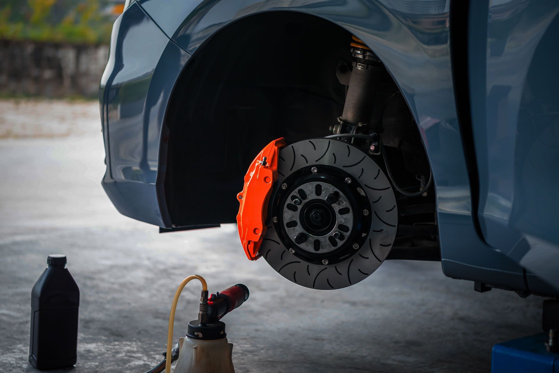 A car is being worked on in a garage with the brake disc removed.