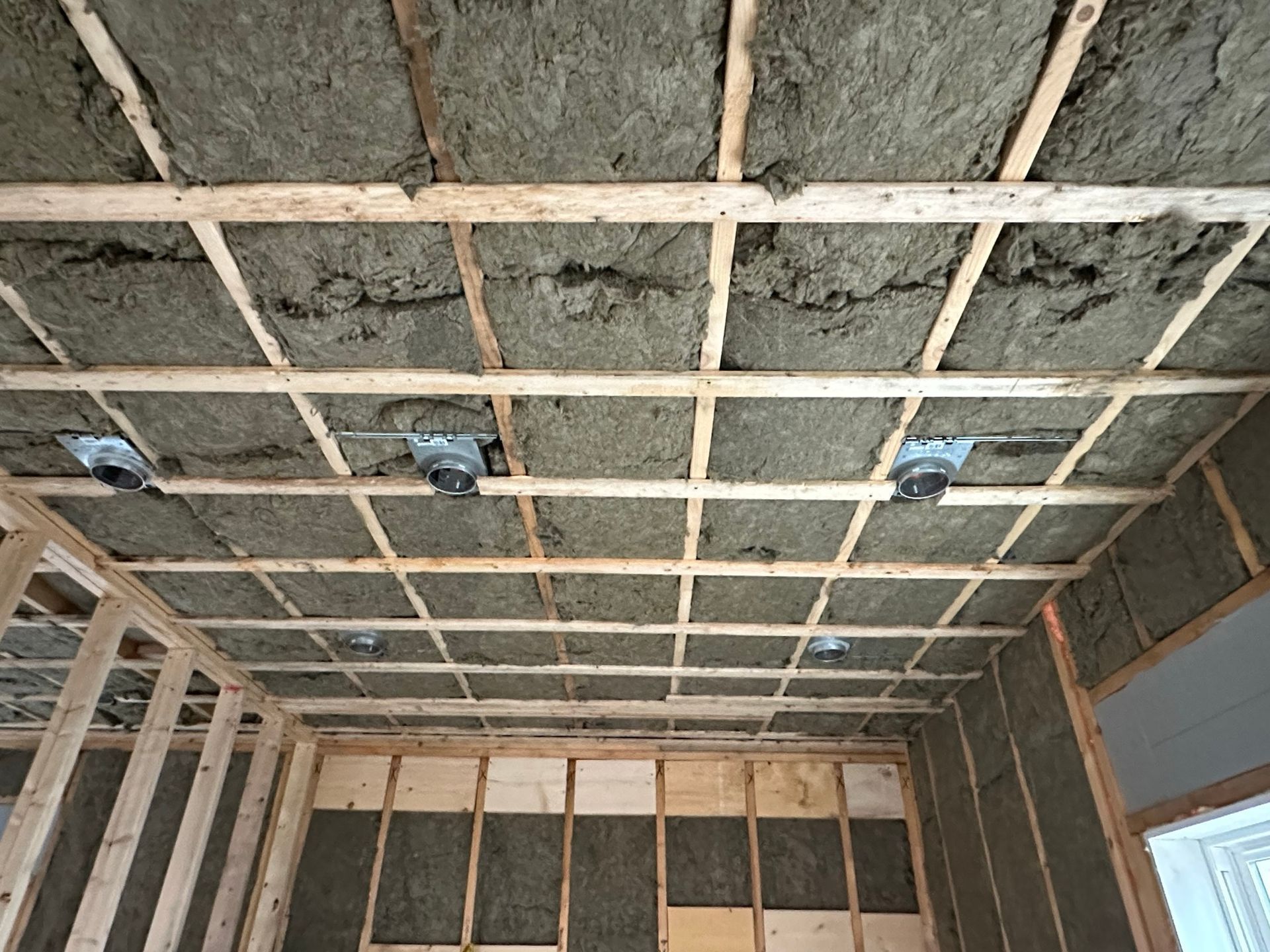 The walls and ceiling of a home are being built with modern framing methods and rockwool insulation.